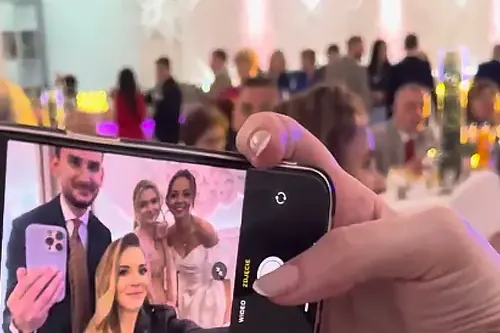 Gość robi telefonem selfie z przyjaciółmi na sali weselnej.